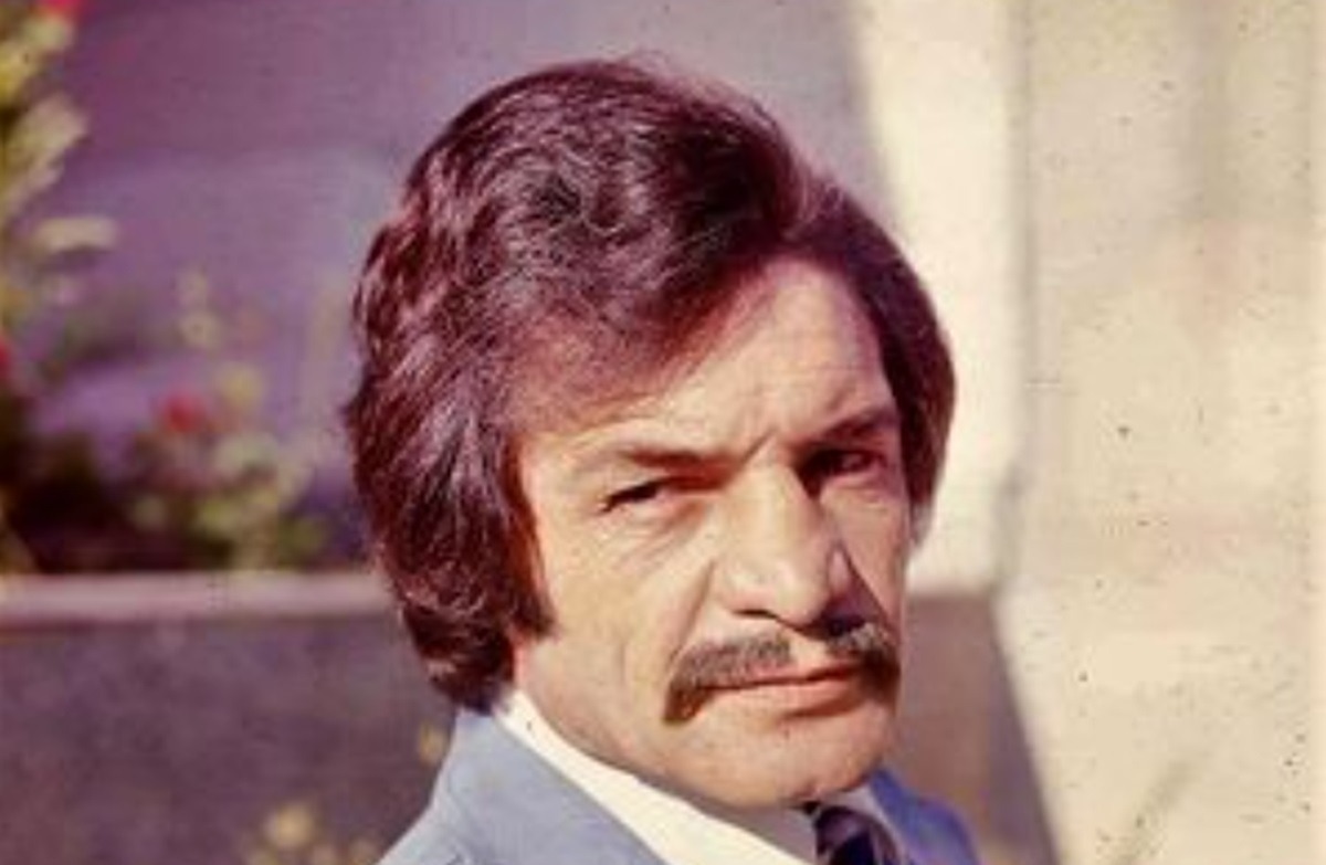 بیک ایمانوردی در حال تمرین قدرتی با هالتر در خانه؛ تصویری از دهه ۴۰